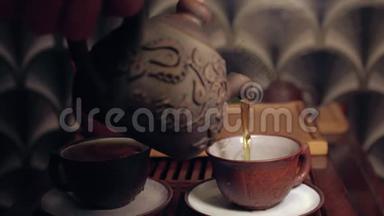 中国传统茶道的动作.. 在一个杯子里用粘土茶壶倒茶。 两个茶壶放在软的焦点上